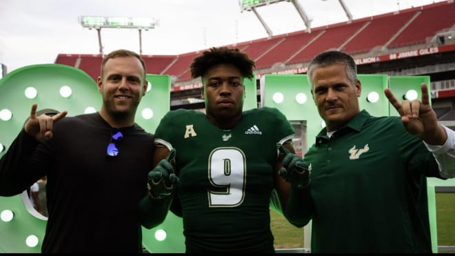 USF coaches Brett Kean and DC Todd Orlando flank Josiah Taylor during his OV