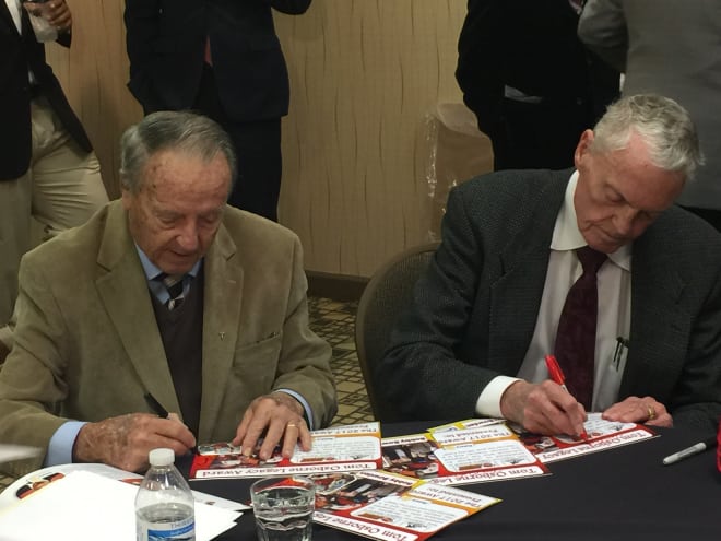 Coaching legends Bobby Bowden and Tom Osborne sign artifacts at the Outland Trophy banquet.