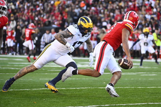 Taulia Tagovailoa (No. 3) is pressured by MIchigan's Braiden McGregor. 