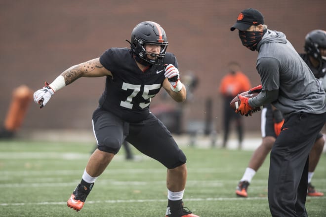 Defensive Coordinator Tim Tibesar (right) works through a drill with defensive lineman Evan Bennett (75, left)