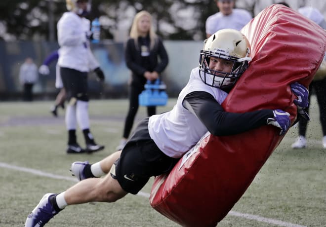 Washington's Elijah Molden smacks into a donut-shaped pad during a drill at the first practice of spring football for the NCAA college team Wednesday, March 28, 2018, in Seattle. (AP Photo/Elaine Thompson)