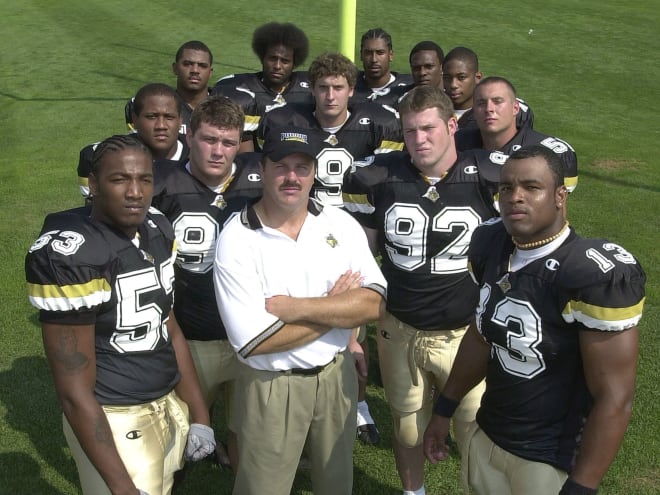 Brock Spack pictured with Akin Ayodele (13), Shaun Phillips (53), Craig Terrill (92) and the 2001 Boilermaker defense. 
