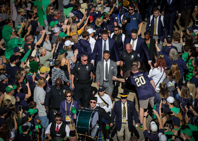 Notre Dame coach Marcus Freeman (center, gray suit) makes his way through the crowd to Notre Dame Stadium before the UNLV game on Oct. 22.