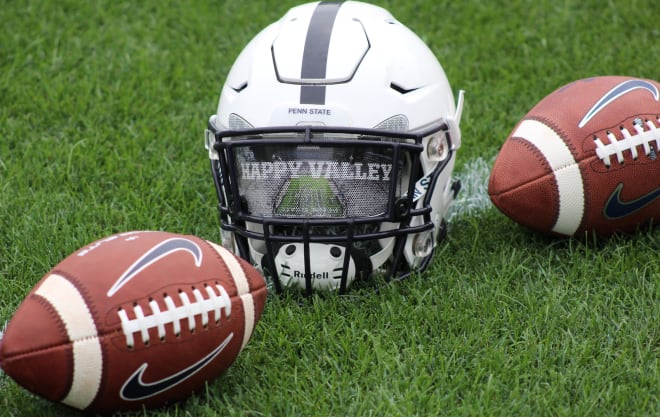 A Penn State football helmet sits between two footballs at the Nittany Lions' media day on Aug. 7, 2021 in State College. BWI photo/Greg Pickel