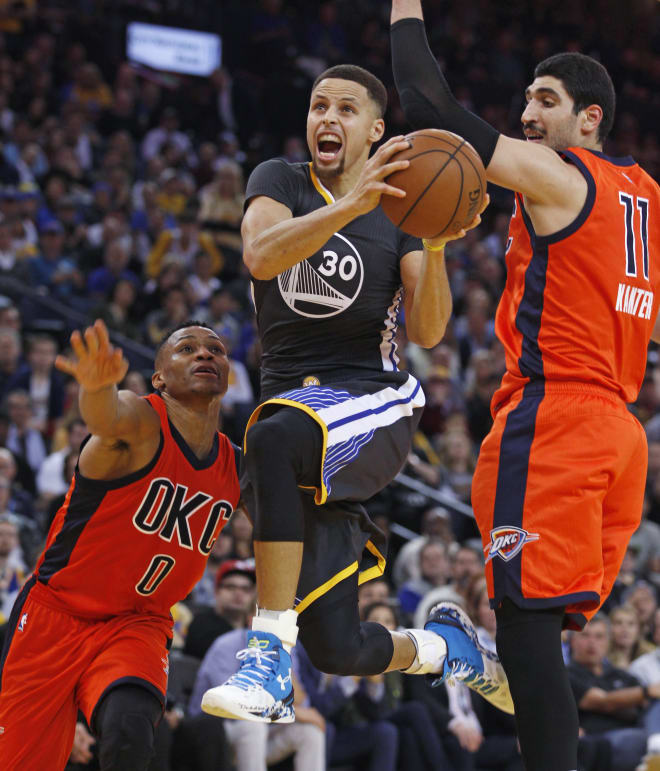 Golden State Warriors guard Stephen Curry drives past Oklahoma City's Enes Kanter (11) and Russell Westbrook Saturday night at Oracle Arena in Oakland, Calif. The Warriors won, 116-108, winning their 41st straight home game and improving to 46-4 on the season.