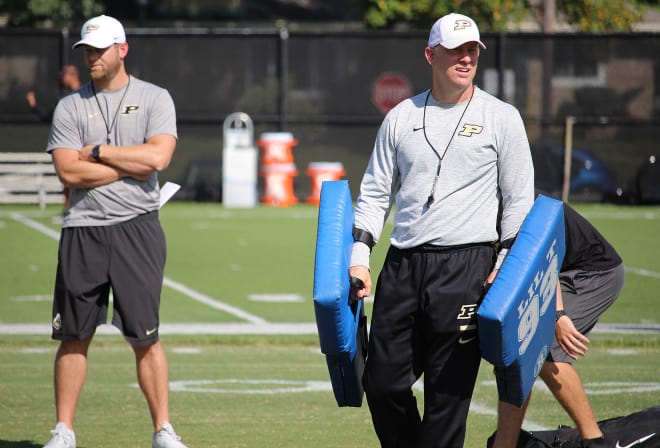 Jeff Brohm, with the blocking pads, are hands-on after with the quarterbacks during practice with his younger brother Brian, who is Purdue's quarterbacks coach.