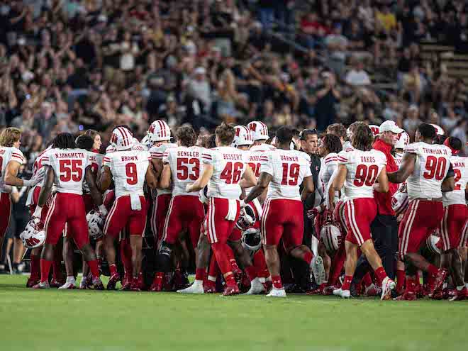 Wisconsin players gather around Chez Mellusi as he's carted off the field. 