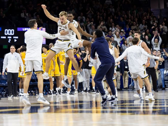 Dane Goodwin, jumping with his arm raised, celebrates with his teammates after the Irish secured a 66-65 win over Lipscomb.