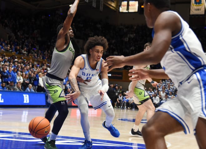 Duke guard Tyrese Proctor, middle, makes a pass through traffic and around defense from Queens' AJ McKee. 