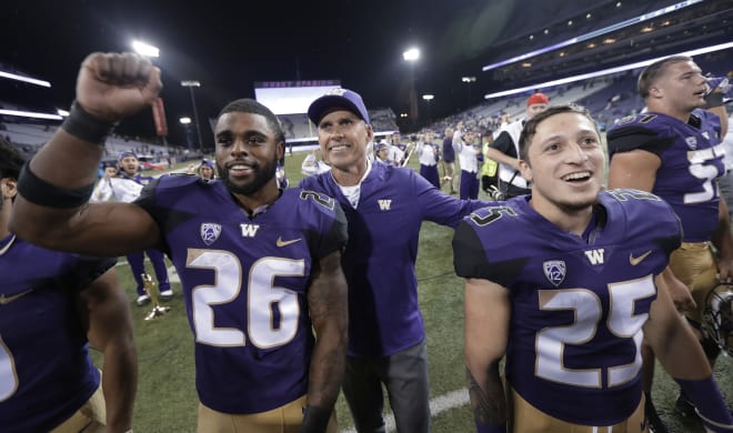 Washington coach Chris Petersen, center, stands with running back Salvon Ahmed (26) and tailback Sean McGrew (25) after an NCAA college football game against BYU, Saturday, Sept. 29, 2018, in Seattle. Washington won 35-7. (AP Photo/Ted S. Warren)