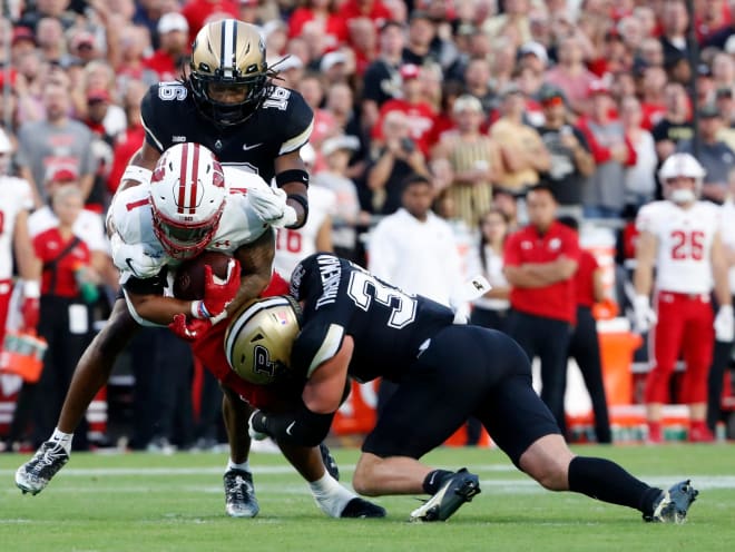 Wisconsin Badgers running back Chez Mellusi (1) is tackled by Purdue Boilermakers defensive back Marquis Wilson (16) and Purdue Boilermakers defensive back Dillon Thieneman (31) during the NCAA football game, Friday, Sept. 22, 2023, at Ross-Ade Stadium in West Lafayette, Ind.