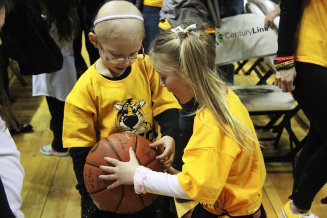 Rhyan Loos and a friend look at the basketball Missouri players signed for her.