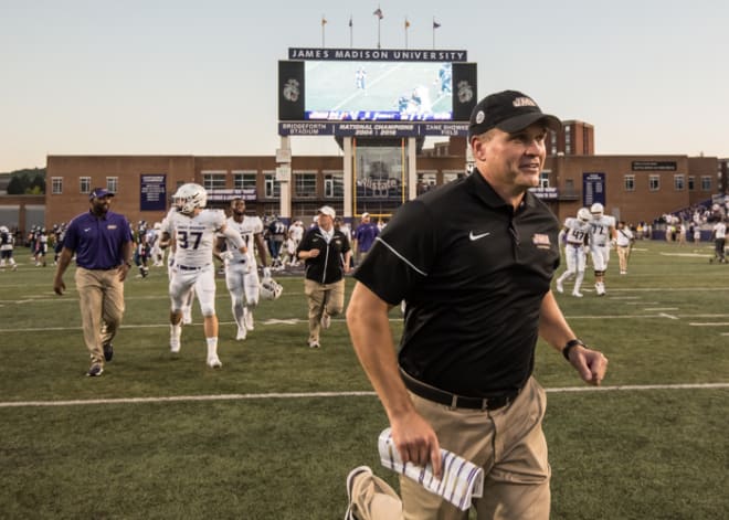 James Madison coach Mike Houston runs to celebrate the Dukes' win with his players this past Saturday at Bridgeforth Stadium in Harrisonburg.