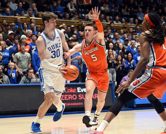 Duke's Kyle Filipowski makes a pass between Syracuse's Justin Taylor, middle, and Maliq Brown, right, on Tuesday night. 