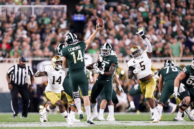 Michigan State's Brian Lewerke passed for 340 yards, but most came after the outcome was well in his hand. Here he had to release a flea flicker too early because of the pass rush from Devin Studstill (14) and Nyles Morgan (5).