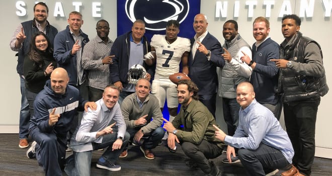 Cain poses with multiple members of Penn State's coaching and recruiting staffs. 
